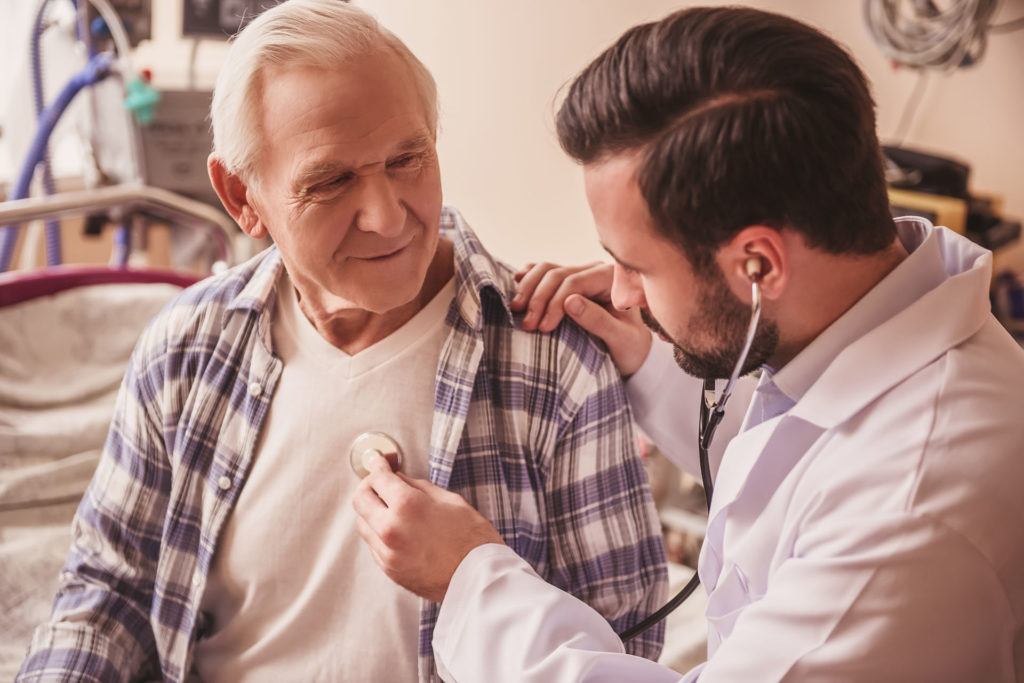 Doctor is listening to the heartbeat of a handsome old man using a stethoscope