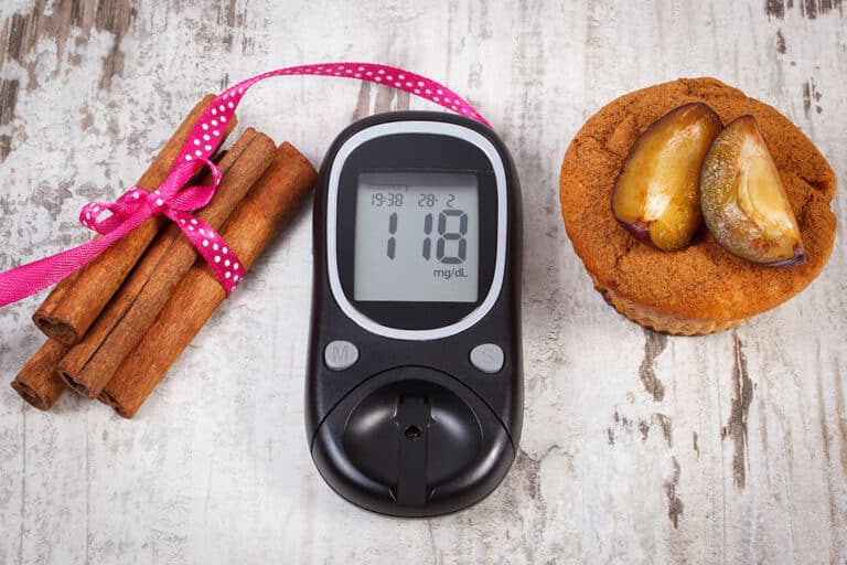 The blood glucose meter is on the table next to the cinnamon