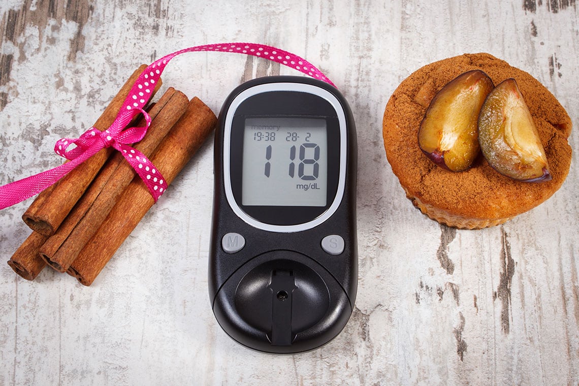 The blood glucose meter is on the table next to the cinnamon