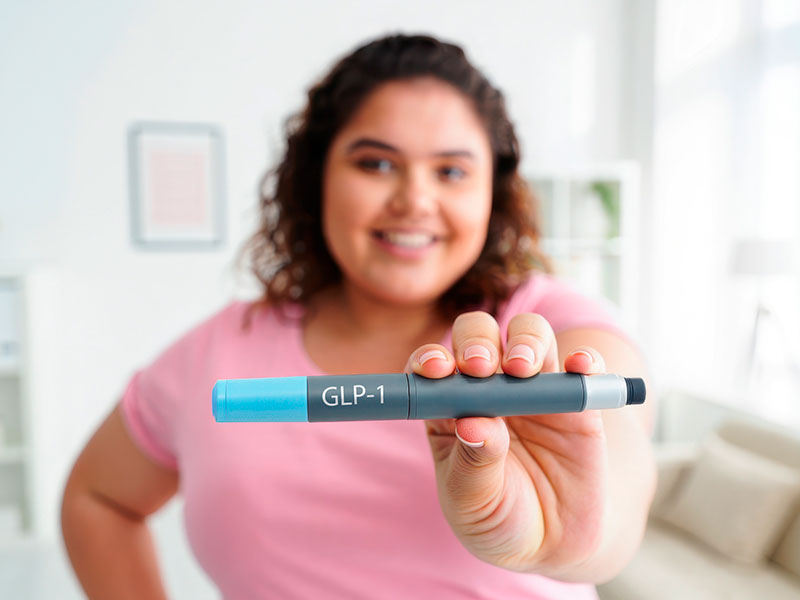 The girl holds an insulin pen and smiles