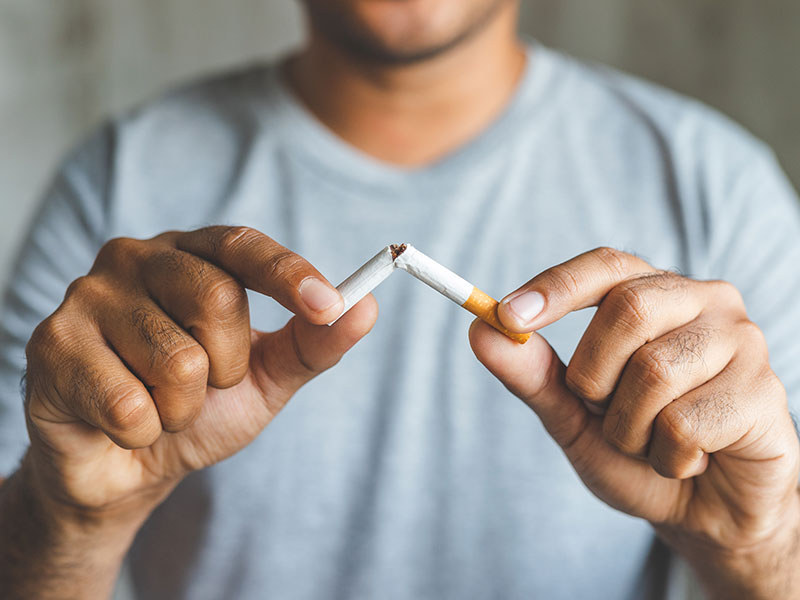 A man holds a broken cigarette in his hands