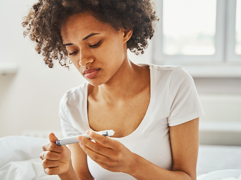 the girl looks at the pen with the diabetes medication, checking if everything is in order with the medicine