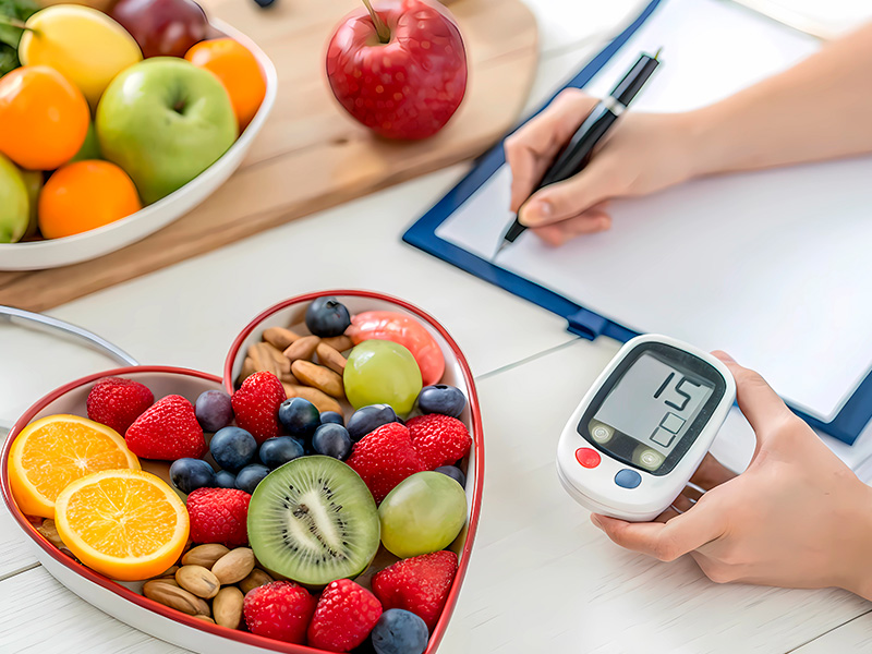 A plate of fruit is on the table and a person records the blood sugar level after measuring it.