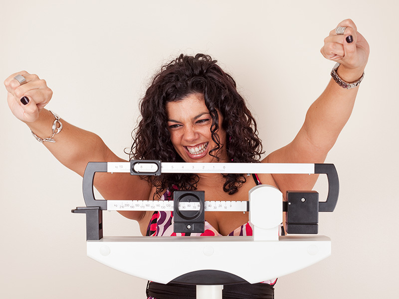A happy girl stands on the scales and smiles