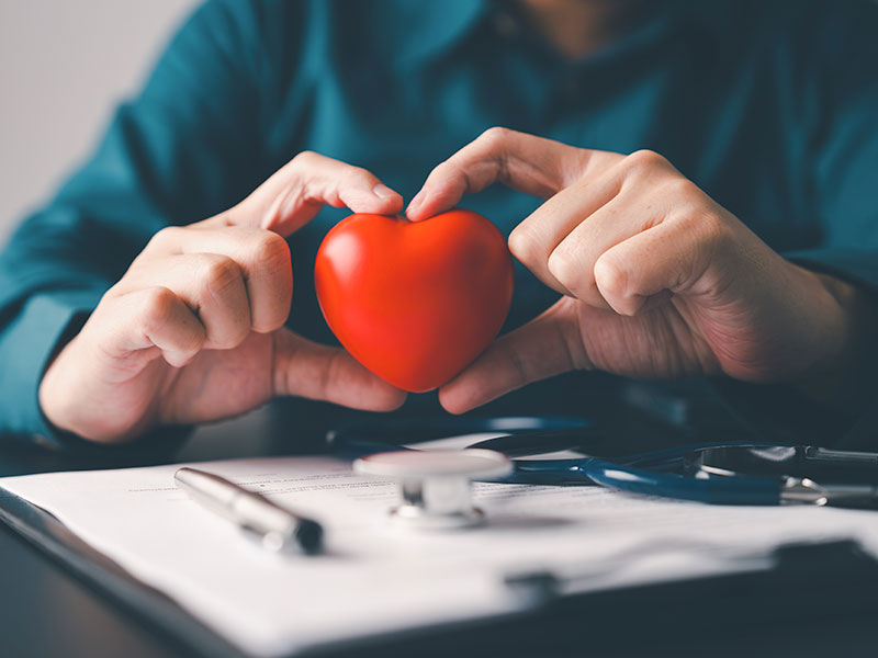 a man holds an artificial heart in his hands, indicating insurance