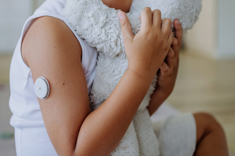 A boy with diabetes hugs a teddy bear
