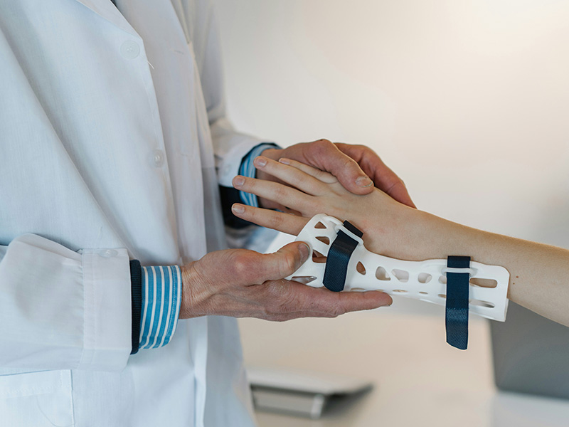 A doctor in a white coat holds a patient's hand after a fracture