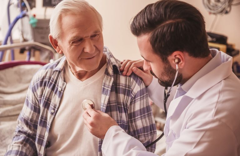 Doctor is listening to the heartbeat of a handsome old man using a stethoscope
