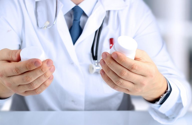Doctor  in a white labcoat choosing  medicament between two drug packagings